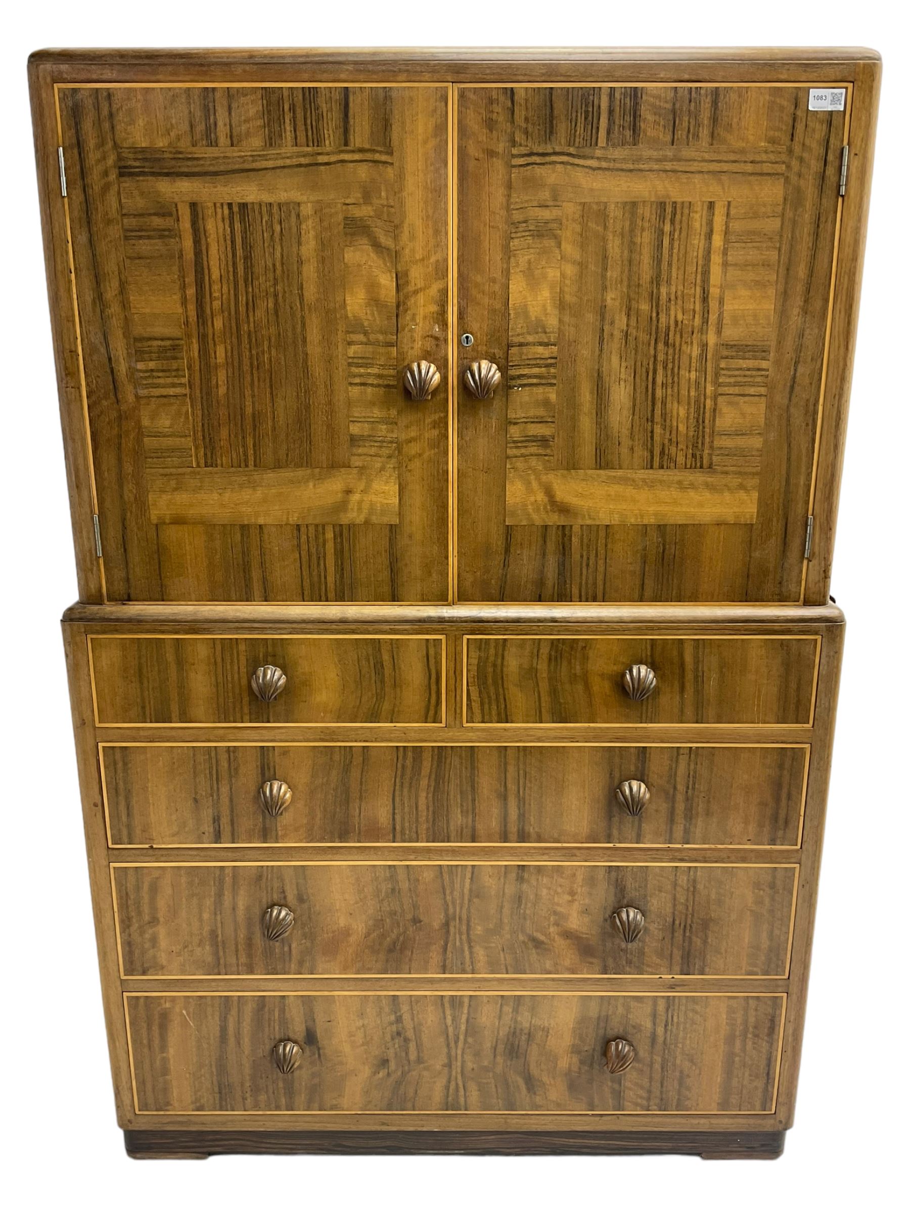 Early 20th century Art Deco walnut cocktail tallboy chest, fitted with double cupboard enclosing two shelves over two short and three long drawers, each with shell shaped handes