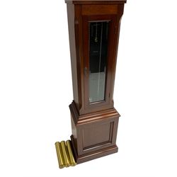 Mahogany cased Grandmother clock c 1980 made and retailed by Julian Stanton, Winchester, with a break arch pediment and corresponding brass dial, full length glazed door displaying three brass cased weights and pendulum, raised on a square plinth with a recessed panel and skirting, German Kieninger three train chain driven movement striking the hours and quarters on 12 gong rods. With weights and pendulum.  