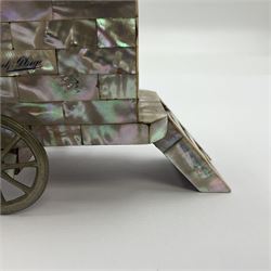 19th century French souvenir jewellery casket in the form of a bathing machine, having mother of pearl panelled tiled effect body, hinged roof/cover revealing a blue silk fitted interior with cushioned base, two silvered metal wheels, abalone shell door and mother of pearl steps, inscribed 'Berck Plage' in blue, H12cm, W13cm 