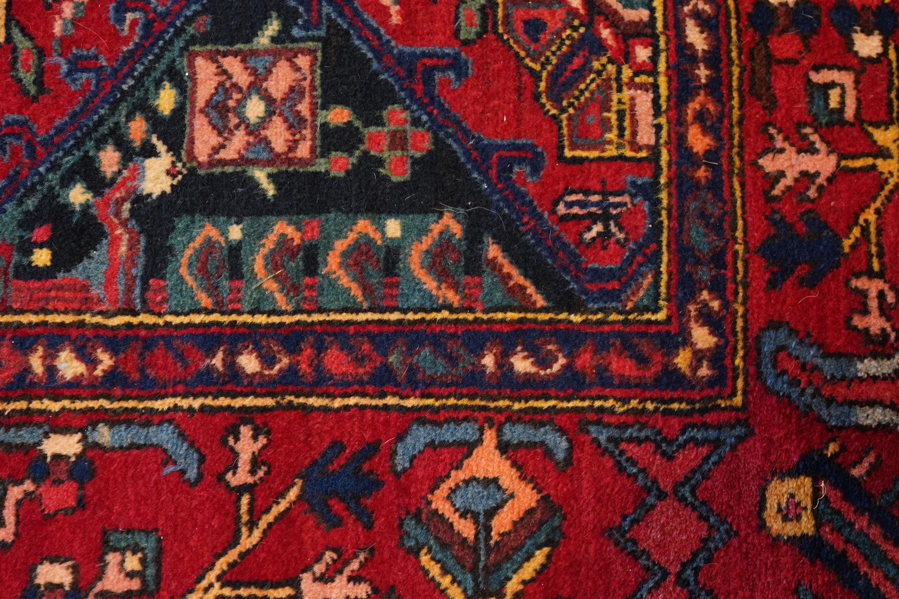 North West Persian Heriz hand-knotted rug, madder red field with an all-over lattice of stepped lozenge medallions enclosing stylized geometric floral motifs and ivory reserve panels, framed by angular vinery and motif borders, main border with with stylized rosettes and geometric devices, flanked by narrow guard stripes,, cotton fringe ends 