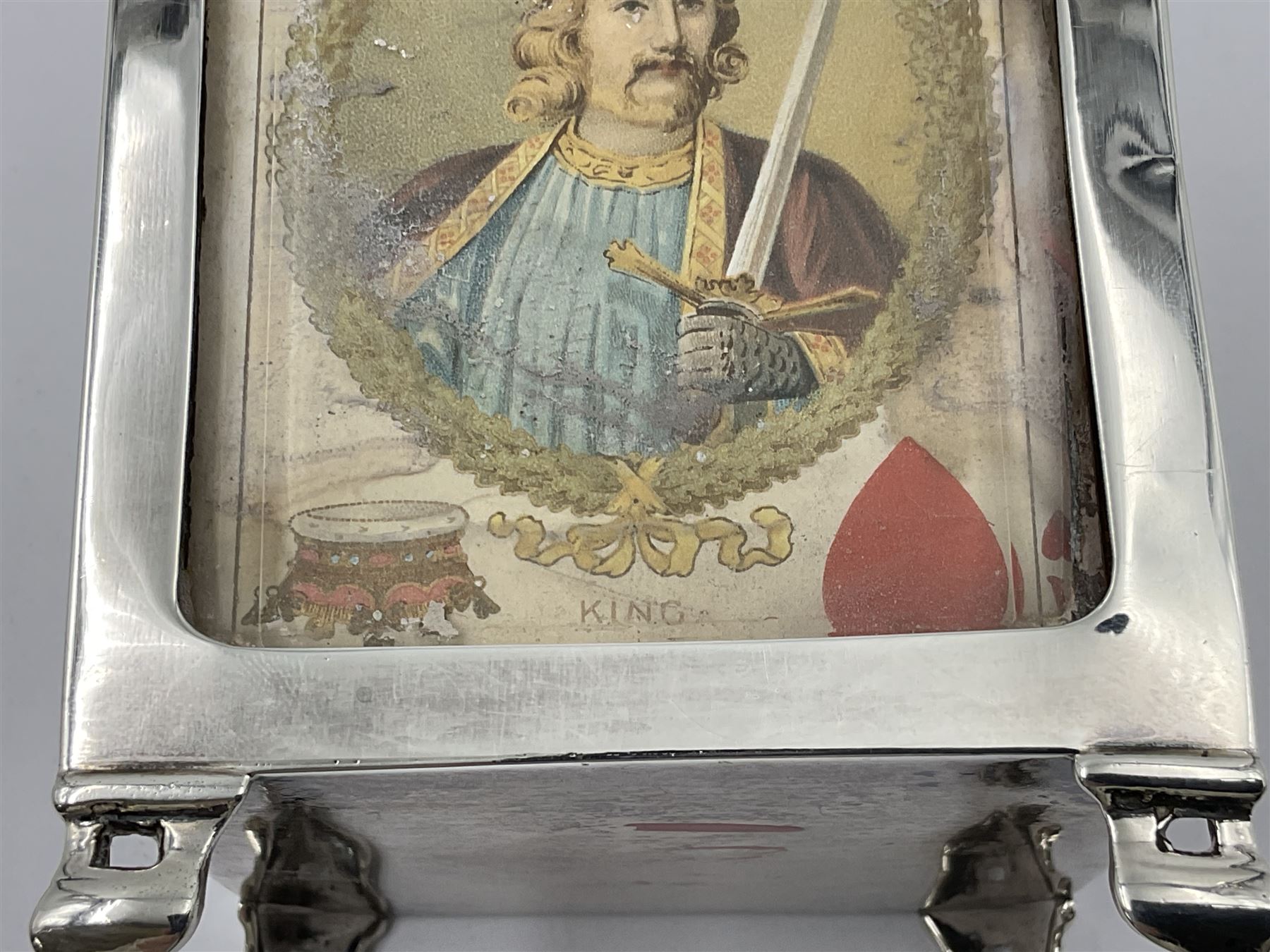 Edwardian silver mounted playing card case, hallmarked William Harrison Walter, Birmingham 1903, the sides each with a period playing card set behind a bevelled glass panel, the hinged cover with later engraving 'Presented to Norman T Crombie Esq by the officers & men of the 31st WR Detachment for services rendered 1917-1918', with red leather lined interior, the three compartments upon a sprung base and containing two later wooden Whist markers, case H12.5cm