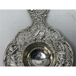 Continental white metal strainer, of shaped form embossed with classical figures, putto, musical trophies and fruiting vines, indistinctly marked, L12.5cm