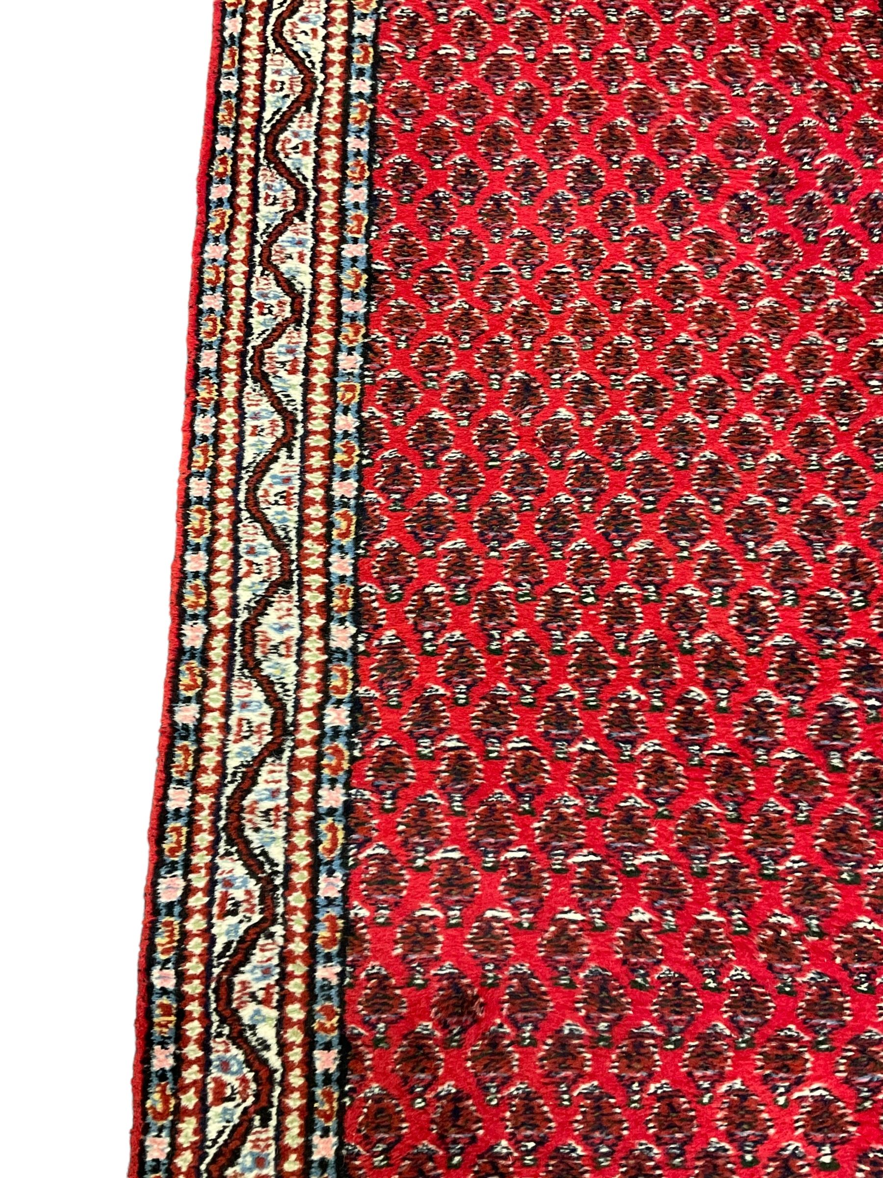 Persian design red ground runner, the field decorated with repeating Boteh motifs, five-band border (277cm x 74cm); Bokhara design red ground rug, decorated with a single row of Gul motifs (272cm x 69cm)