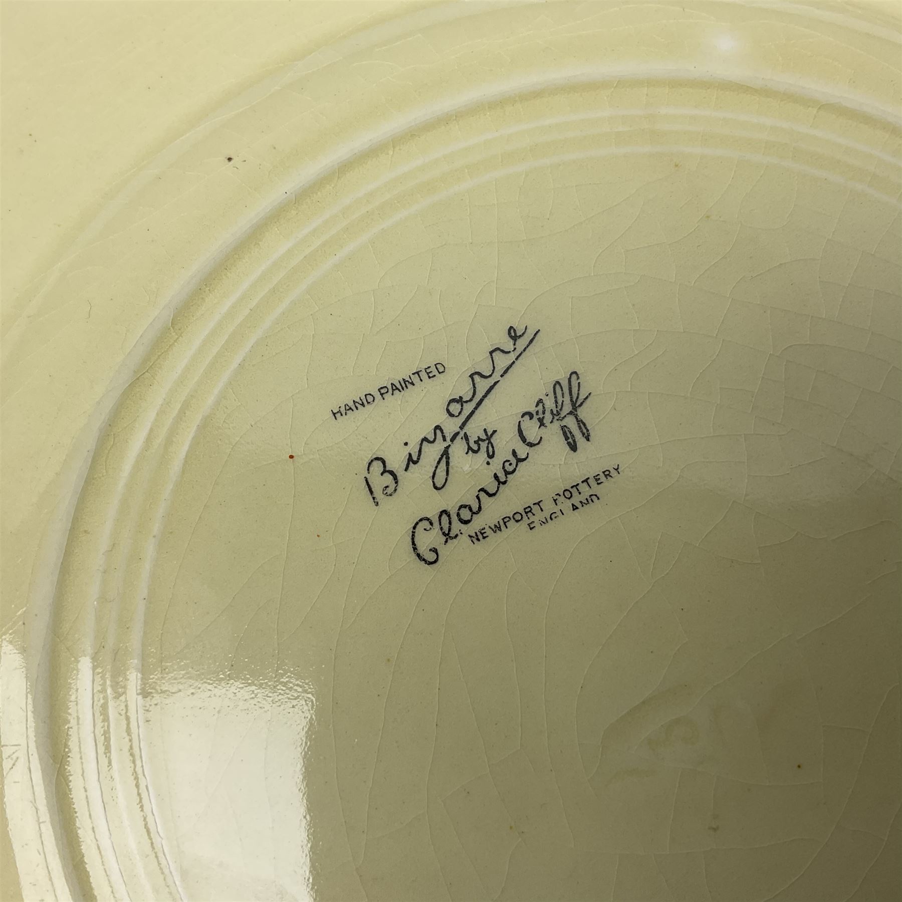 Clarice Cliff Bizarre for Newport Pottery Orange Roof Cottage pattern plate, circa 1932, hand painted with a stylised cottage and bridge landscape with yellow, orange and black banding, black printed mark beneath, D22cm 