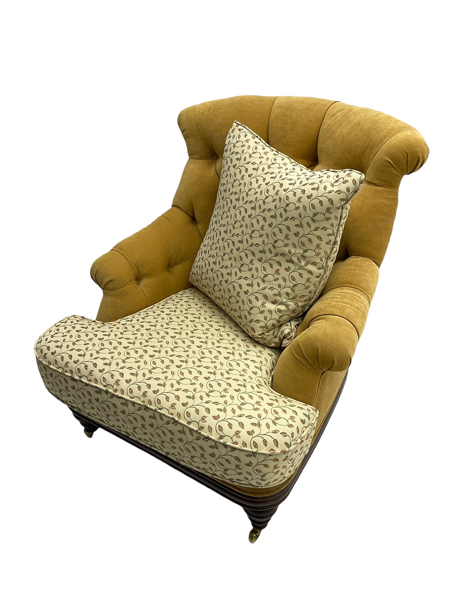 Victorian style armchair, upholstered in buttoned fabric with contrasting foliate pattern seat and scatter cushion, on turned front feet with castors