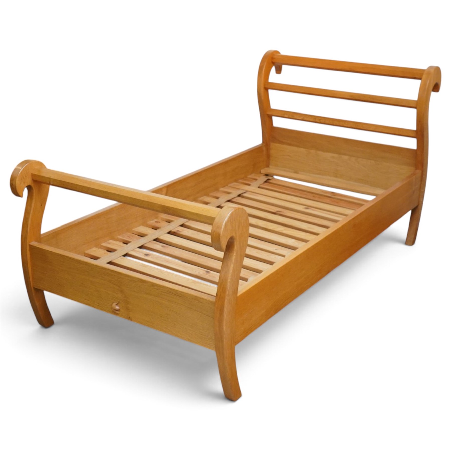 Unicornman - pair of craftsman-made oak single beds, of sleigh shape with scrolled head and foot-boards with octagonal stretchers, slatted base, raised on inward-splayed squared supports, applied with carved unicorn signature, by Geoff Gell of Coxwold