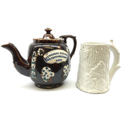 A 19th century Barge Ware teapot, decorated with applied floral sprays and thistles against a mottled brown ground, and plaque detailed Catherine Taylor God Bless Our Home 1890, H18cm, together with a white glazed puzzle mug, H15cm. 