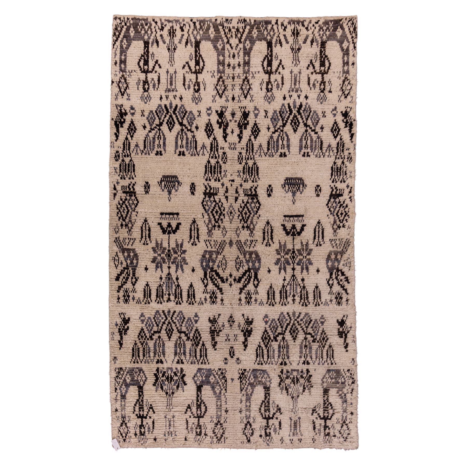 Moroccan hand-knotted Berber rug, of rectangular form, ivory ground woven with horizontal bands of stylized tribal motifs, including abstract animals and anthropomorphic figures, interspersed with geometric devices, with fringe ends 