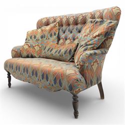 Late 20th century Liberty upholstered two seater sofa, the shaped back and arms with deep buttoned upholstery, covered in Art Nouveau fabric with stylised floral and foliate motifs, loose scatter cushions en suite, raised upon turned tapering front supports and swept rear legs