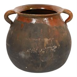 Three early 20th century Spanish part glazed terracotta storage vessels, the first example of bellied form with rounded base and twin loop handles, H24cm, the second of baluster for with close set loop handles, H30cm, and the third smaller also of baluster form with single loop handle, H24cm