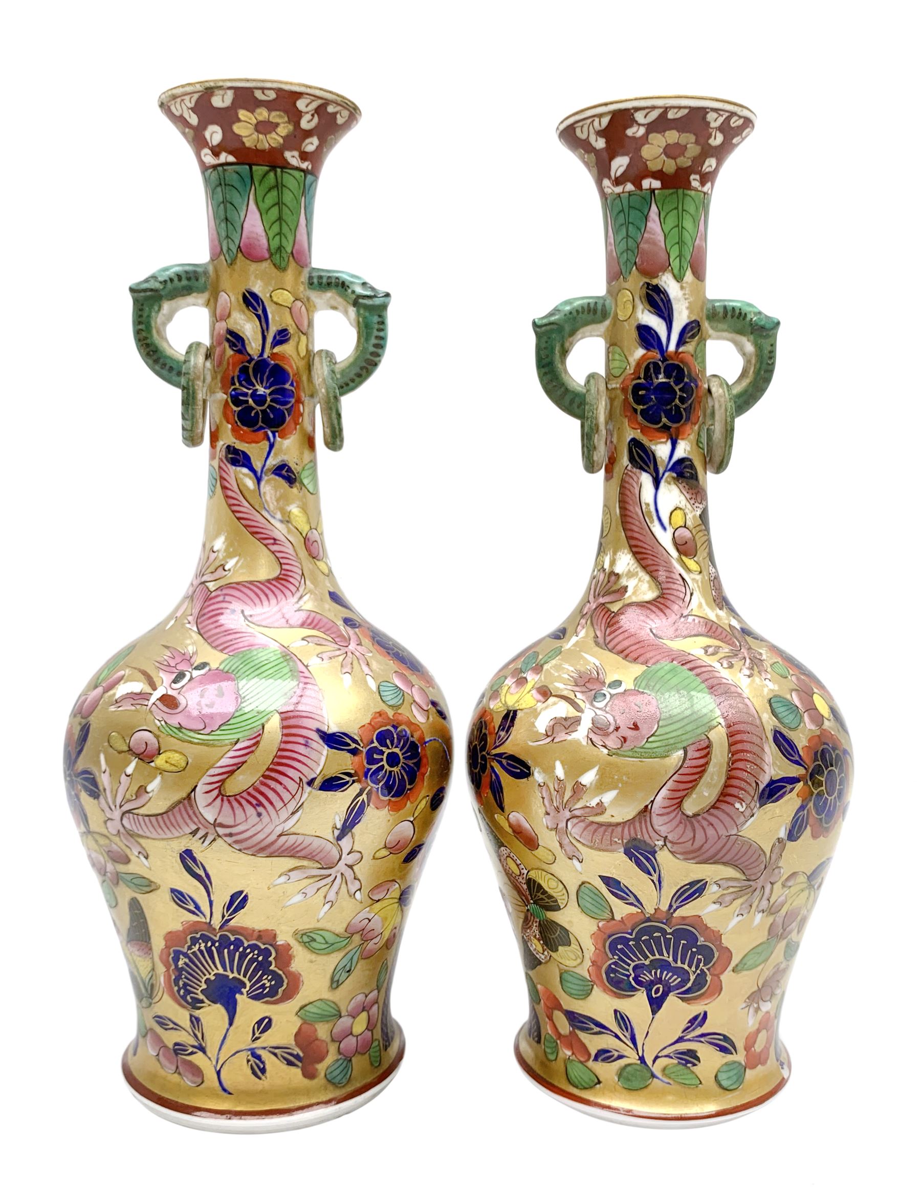 Pair of early 19th century Miles Mason vases, the baluster bodies with tall slender necks supporting twin stylised trunk handles with rings, decorated with Chinese dragons, butterflies, and blossoming flowers against a gilt ground, with spurious Chinese marks beneath in iron red, H27.5cm