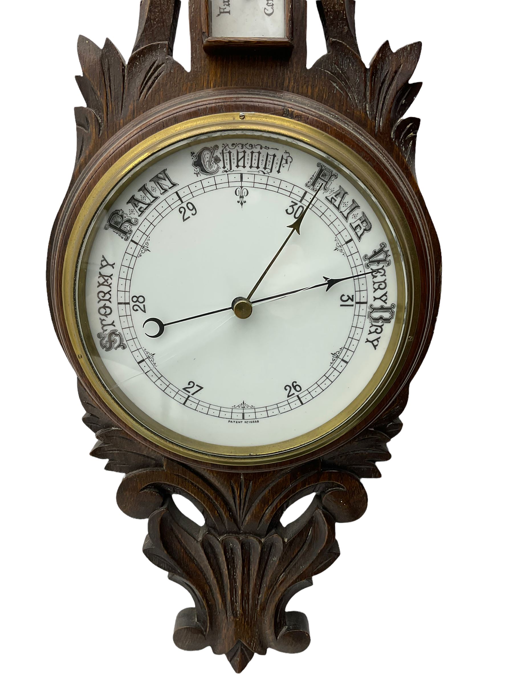 A 1920s oak cased patented aneroid barometer with openwork decorative carving, 8” enamel dial recording air pressure from 26 to 32 inches with weather predictions in gothic script, steel indicating hand and brass recording hand within a brass bezel and flat glass (glass cracked), with a boxed mercury thermometer recording the temperature in degrees centigrade and Fahrenheit.    

