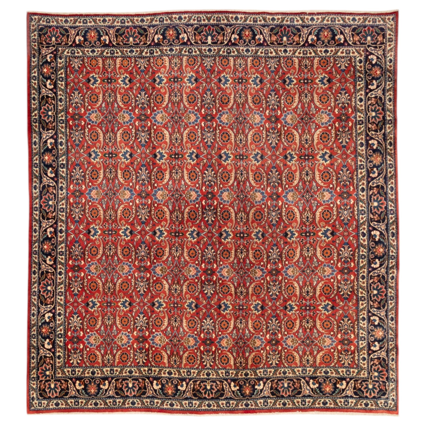 North West Persian carpet, the red field decorated with an all over repeating design of palmettes, rosettes and curling serrated leaves in indigo, ivory and ochre tones, enclosed by an indigo scrolling floral border and ivory flowerhead guard bands