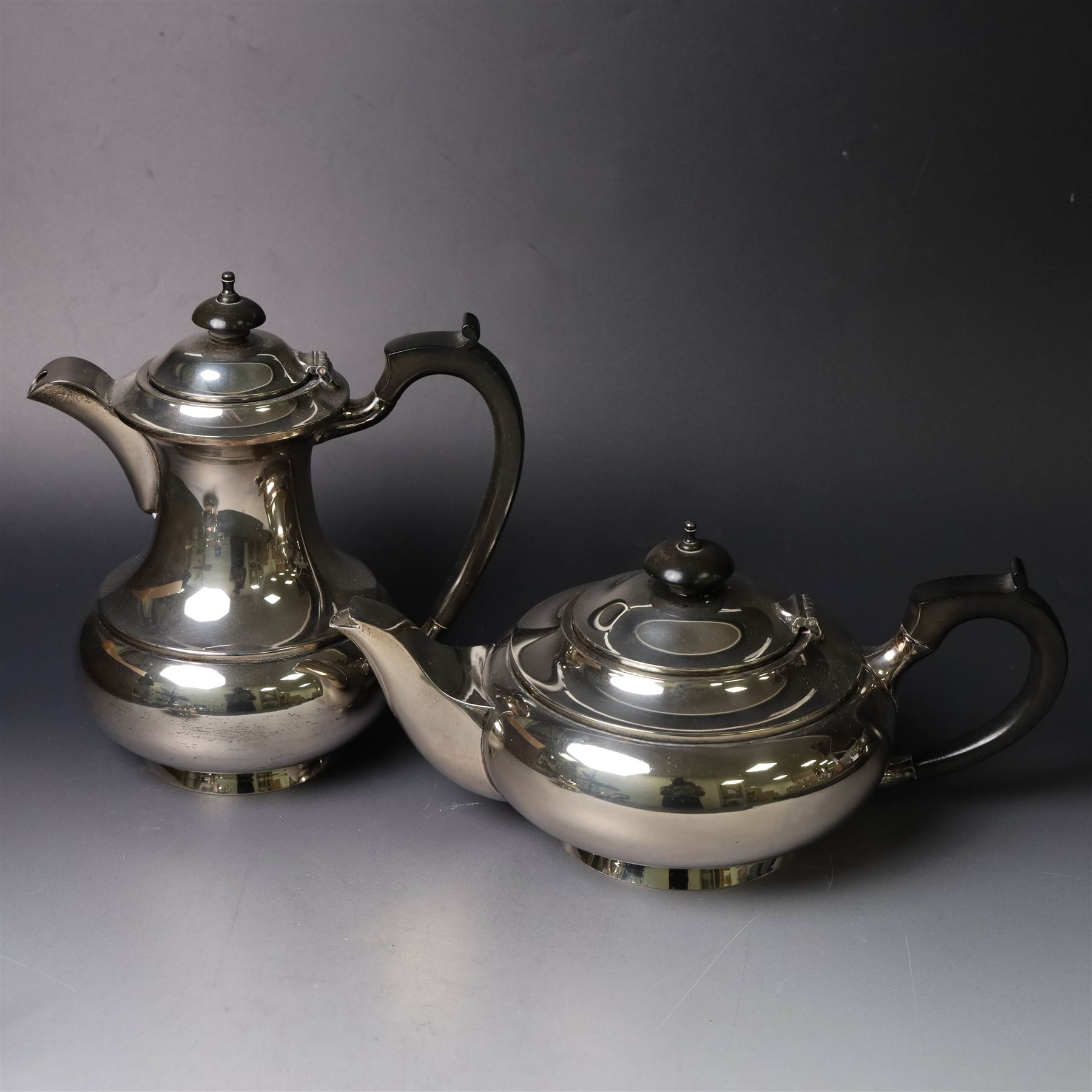 Mid 20th century silver four piece tea service, comprising teapot, hot water pot, open sucrier and milk jug, all of squat bellied form, the teapot and hot water pot with ebonised handles and finials, hallmarked Walker & Hall, Sheffield 1953, hot water pot H19cm