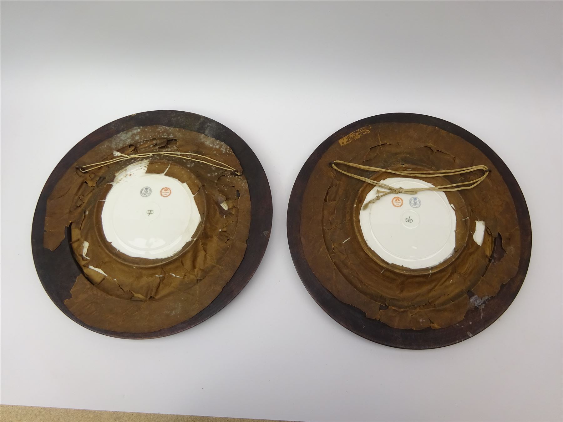 Pair mid 19th century Sevres porcelain plates, with gilt Louis Phillippe crowned monogram to centre upon a white glazed ground, with blue crowned LP mark, iron red destination mark for Chateau D'Eu, and chrome green cancelled potting mark S67 beneath, in carved oak mounts, overall D34cm
     
