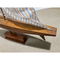 Large pond yacht with simulated planked mahogany deck, mahogany hull, wooden keel and stern fin and tubular aluminium mast with two sails; on wooden stand L131cm H on stand 177cm