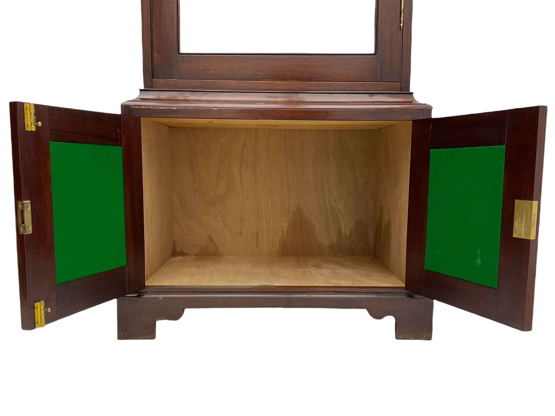 Mahogany display cabinet with hidden compartment, projecting cornice over single glazed door enclosing glass shelves, double panelled cupboard below, the interior with button releasing sliding back compartment, on bracket feet