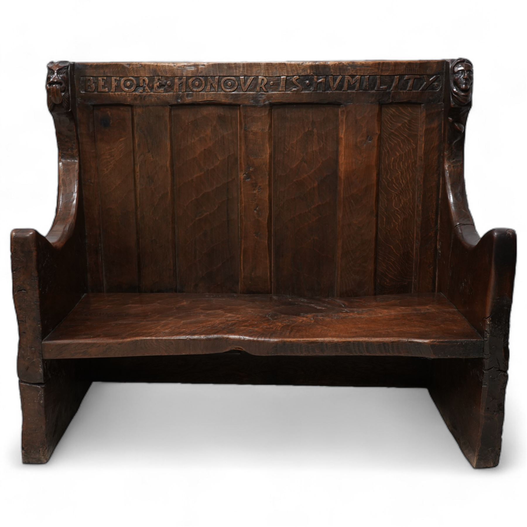 Mouseman - circa. 1920s adzed oak settle or bench, the cresting rail carved with inscription 'Before Honour is Humility', four panel back and plank seat on shaped end supports carved with grotesque masks terminals, carved with mouse signature, by Robert Thompson of Kilburn 
