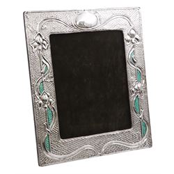 American Art Nouveau silver mounted photograph frame, of rectangular form, with oblique gadrooned rims, embossed iris flowers and vacant oval cartouche, interlaced with ribbons and green blue enamel, upon hobnail effect ground, with hardwood easel style support verso, stamped Sterling