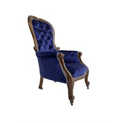 Victorian armchair, spoon back and scrolled arm terminals, upholstered in indigo buttoned velvet with sprung seat, raised on cabriole supports on castors