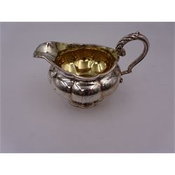George IV silver milk jug, of squat circular fluted form, with engraved monogram to body, gilt interior and acanthus capped scroll handle, upon lobed foot, hallmarked London 1829, maker's mark worn and indistinct, including handle H10cm