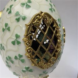 Franklin Mint The Emerald Isle Collector Egg, the egg decorated with embossed shamrocks upon a cream ground, with a gilded shamrock finial, accents and openwork door, opening to reveal a miniature landscape scene, upon three gilded feet set with green paste stones, with certificate of authenticity H23cm, 