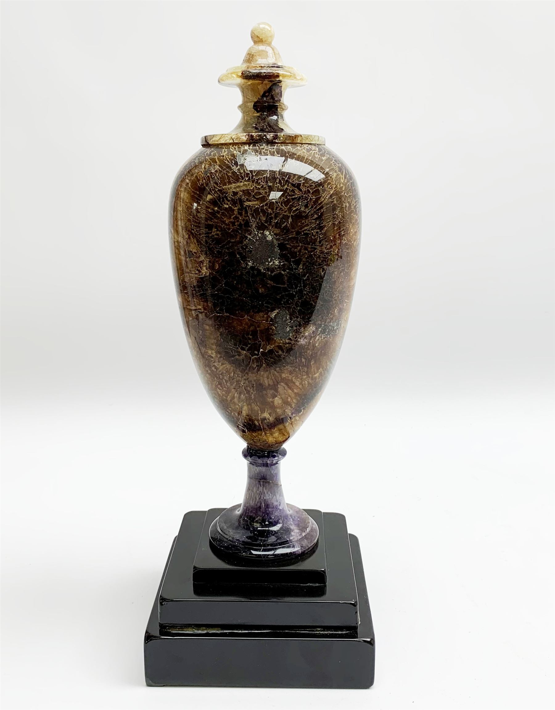 Early 19th century and later Blue John urn, Winnats one vein, of ovoid form with integrated cover and ball finial, upon a spreading circular base, and square stepped black lacquered base, H34.5cm