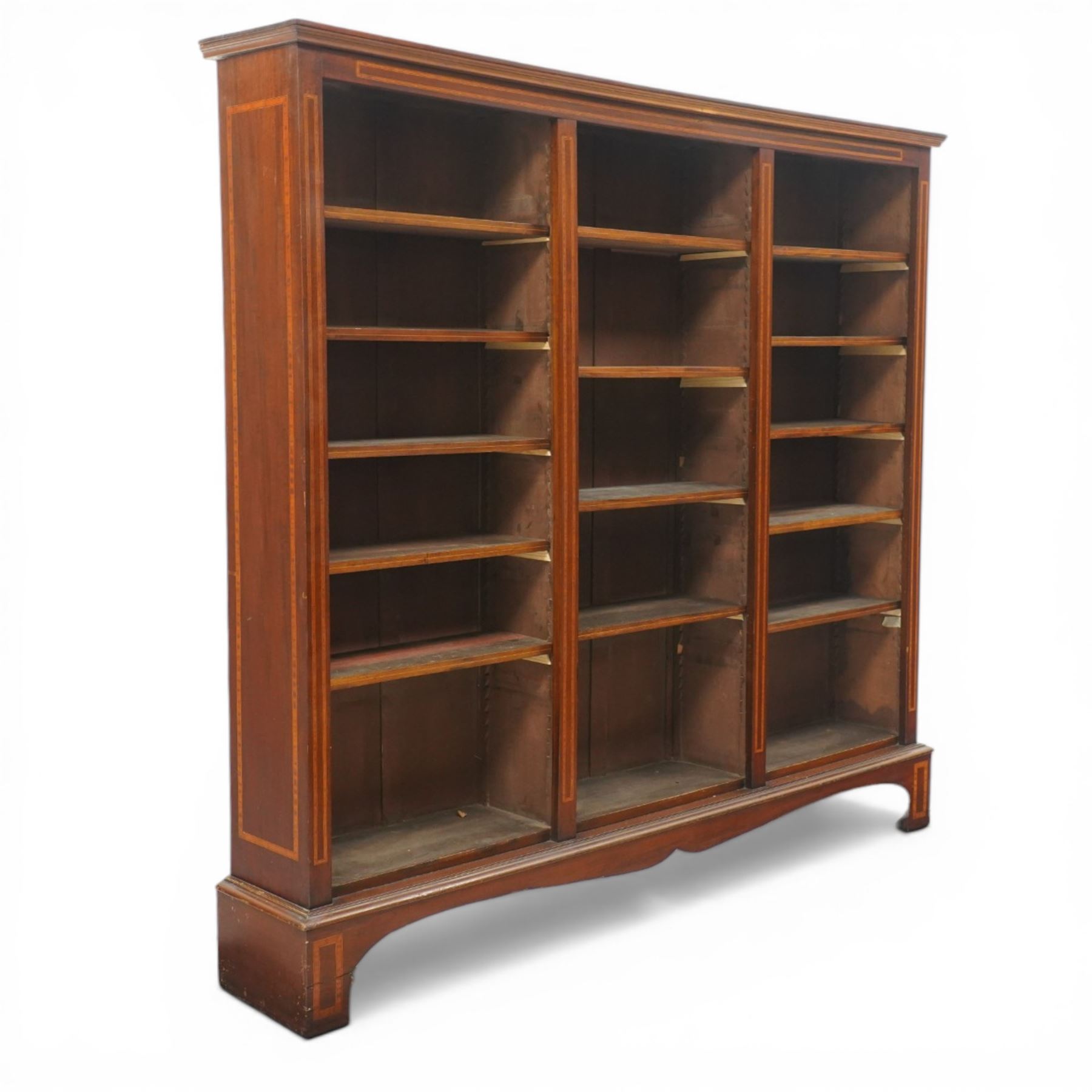 Quality Edwardian inlaid mahogany triple-column open bookcase, projecting cornice over a satinwood banded frieze, fitted with fourteen adjustable shelves with strung facias, the shaped apron on bracket feet