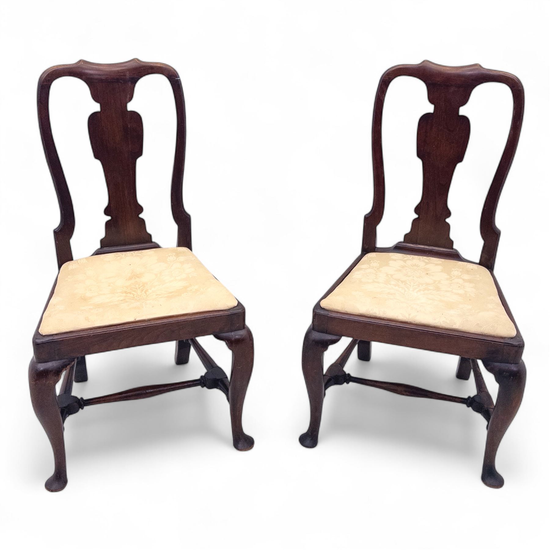 Pair of early 18th century walnut side chairs, vase-shaped splats beneath shaped top rails, drop-in seats upholstered in floral damask, on cabriole front legs terminating in pad feet, united by turned stretchers