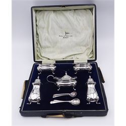 1920's silver five piece cruet set, comprising two peppers, two open salts with blue glass liners, and mustard pot and cover with blue glass liner, each upon four pad feet, hallmarked Walker & Hall, Birmingham 1926, and three cruet spoons, hallmarked Walker & Hall, Sheffield 1926, contained within a fitted case, approximate silver weight 5.90 ozt (183.6 grams)