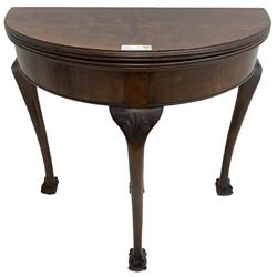 Early 20th century figured walnut demi-lune card table, fold-over reed moulded top with baize lined interior, pull-out rear support with storage well, on shell carved cabriole supports with ball and claw feet