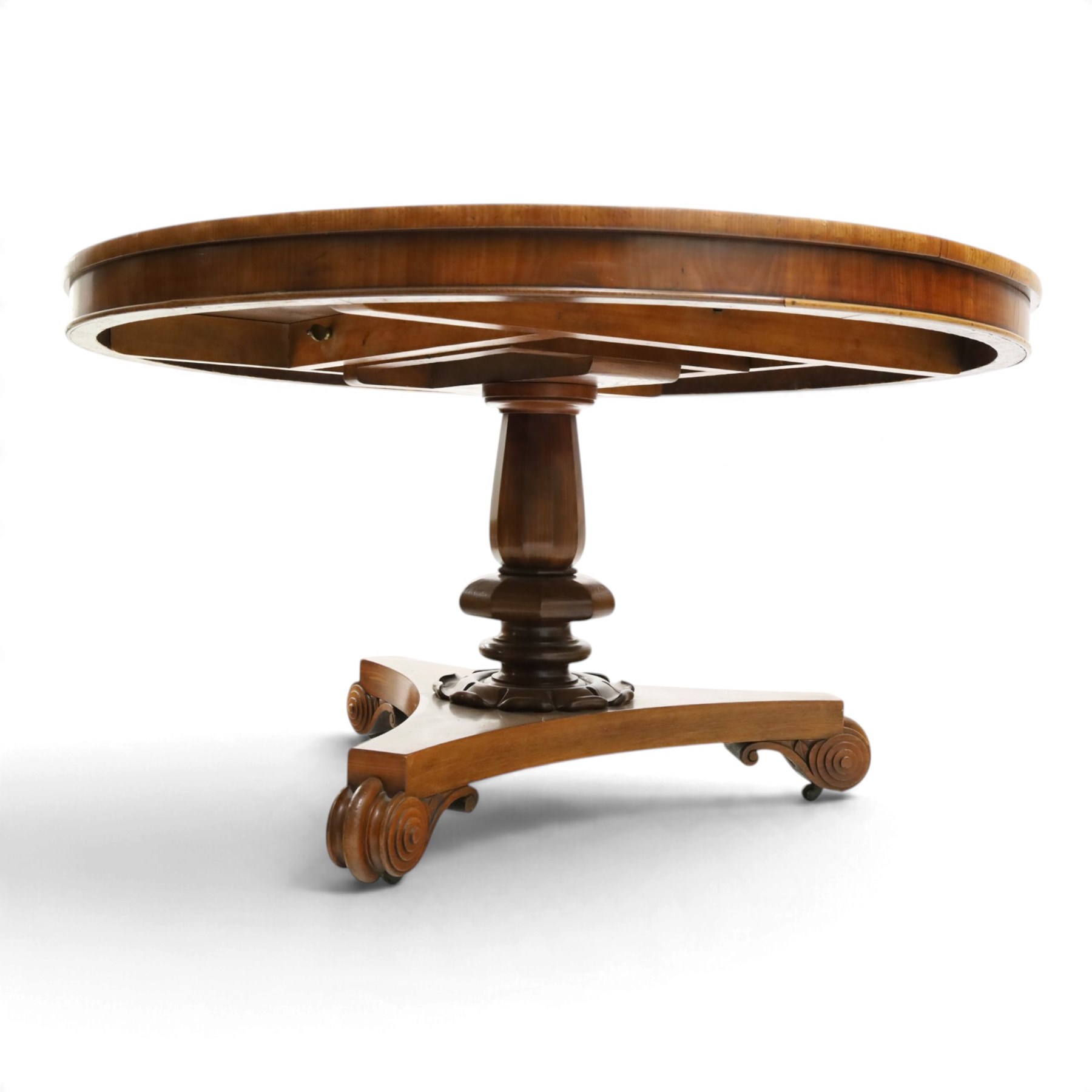 William IV mahogany circular breakfast table, banded frieze over a turned decagon pedestal with lappet carved collar, terminating to a triform platform base with scroll feet and castors