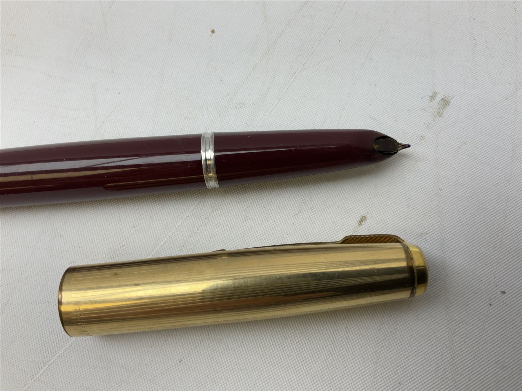 Five Parker fountain pens with gold caps, to include 65 Consort Insignia with rolled cross hatch gold cap, two Parker 51 fountain pens in burgundy with 12ct rolled gold caps, together with two further 51 examples in blue and black, all with stamped lids