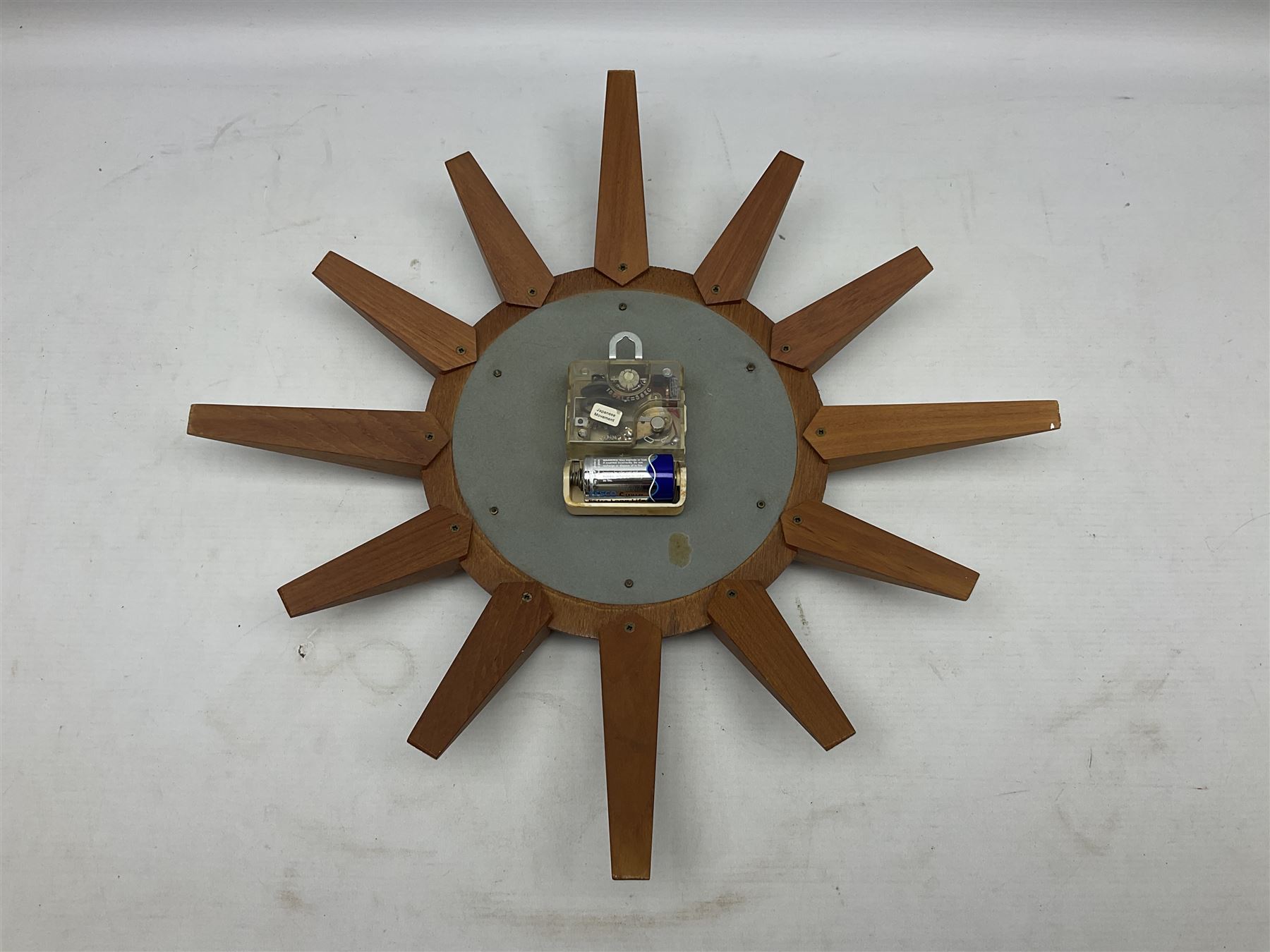 Mid-century teak sunburst wall clock by Anstey & Wilson, modelled with angular teak rays spreading from circular mount with plain brass face with Roman numerals, with battery operated Japanese movement, D45cm