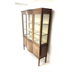 Early 20th century mahogany, inlaid and cross banded break bowfront display cabinet, projecting cornice over two glazed doors and central curved glass panel, lined interior, cupboards below, square tapering supports