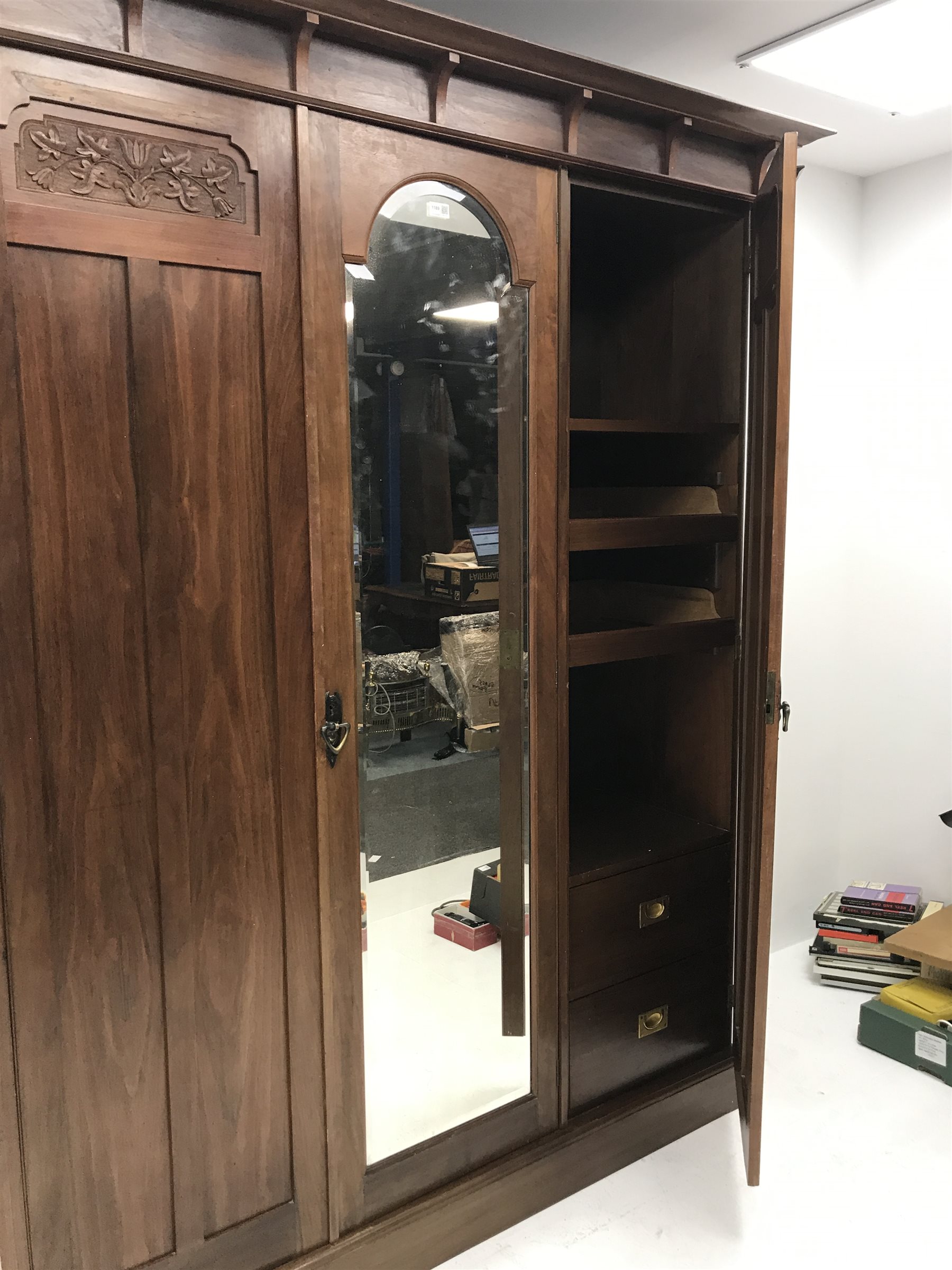 Irish Arts & Crafts walnut triple wardrobe circa 1908, projecting cornice above three doors enclosing fitted interior, single full length bevel edge mirror, platform base, W173cm, H204cm, D56cm