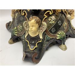 Composite table lamp modelled as a Roman Emperor donning blue robes, upon quatrefoil base modelled with rams heads and winged cherubs, H56cm excl fitting