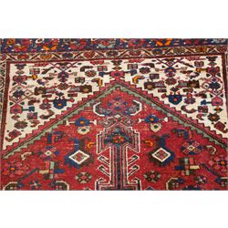 Persian Heriz crimson ground carpet, the central navy geometric medallion on a red crimson ground field, surrounded by further geometric stylised motifs and foliate designs, enclosed by multiple guard-lines  