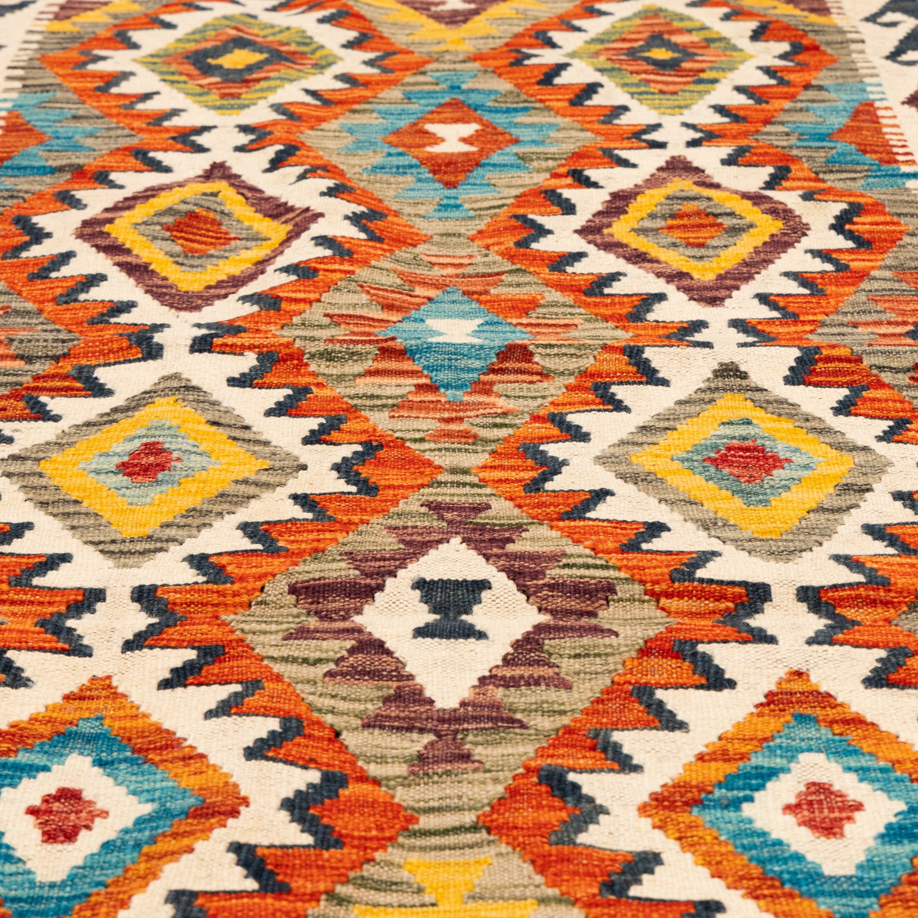 Afghan kilim ivory ground runner rug, the field with three columns of repeating lozenge motifs with amber and multicoloured tones, enclosed by a guard band decorated with repeating stylised hooks