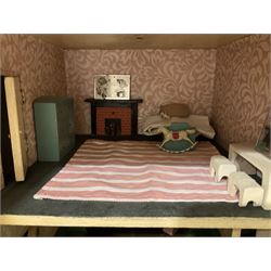 Large Tri-ang No.93 doll`s house in the 'Stockbroker's Range' c1935; two-storey double-fronted Tudor design, half timbered gables, two-storey bay windows, cream and mock shrubbery to front, opening metal framed windows with green shutters, red simulated tiled roof with chimney, integral garage with opening doors, front elevation has four hinged doors opening to reveal two bedrooms with fire places, living room, bathroom and kitchen with built in dresser and sink, entrance hall and staircase, side entrance with porch and seat and sun dial over on chimney stack; some wiring for electrical lighting; metal Tri-ang Toys disc verso; comprehensively furnished H66cm L117cm D43cm