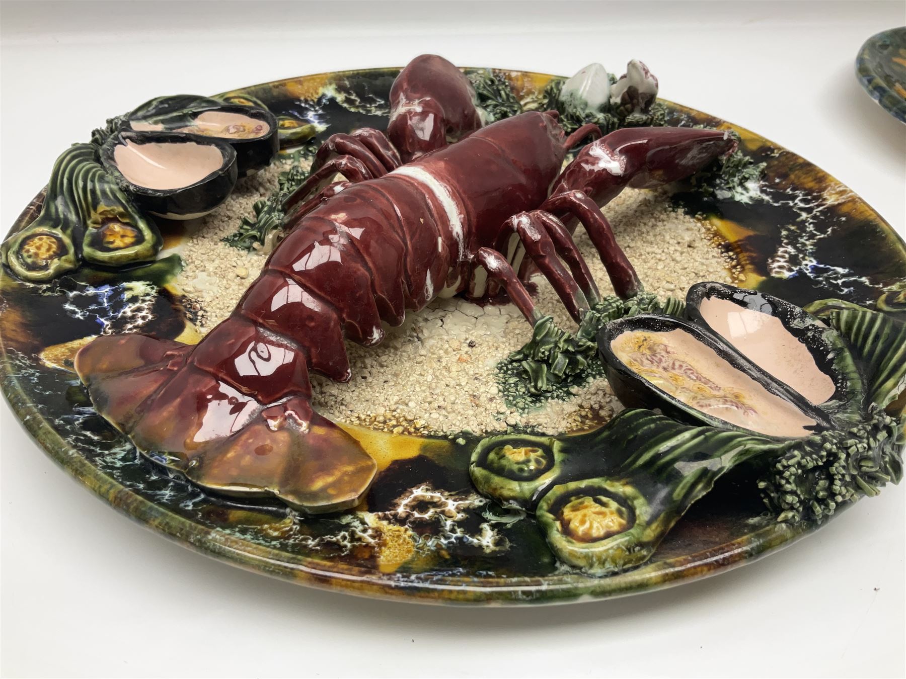 Two 20th Century Portuguese Palissy style Majolica wall plates, one depicting a crab, the other a lobster each to the centre modelled in relief surrounded by encrustations and shells, both with impress marks beneath, D32cm