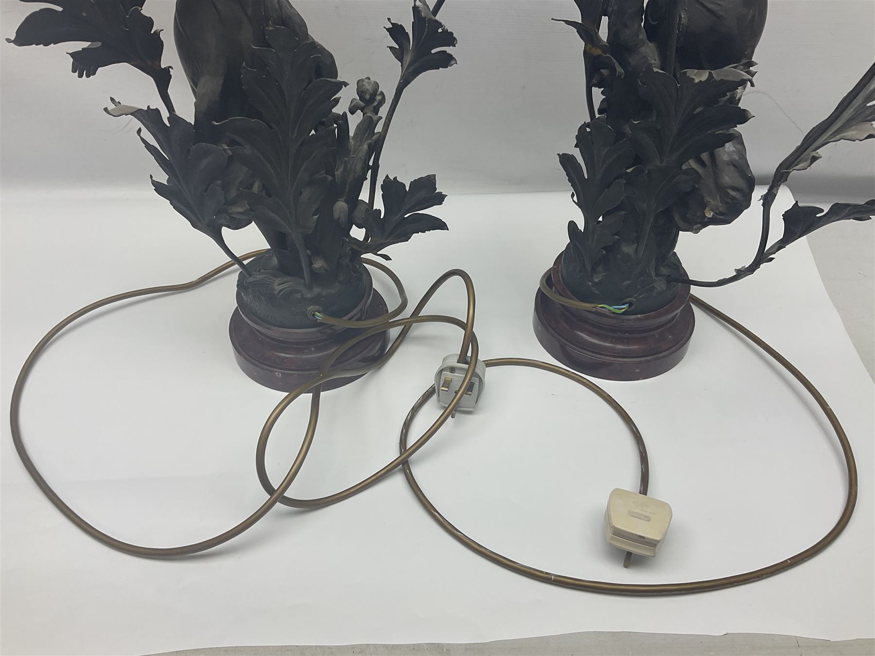 Pair of Art Nouveau style spelter figural table lamps, each mounted on rouge marble effect circular bases, with toleware flower heads and leafy decoration surrounding a female figure, H90cm