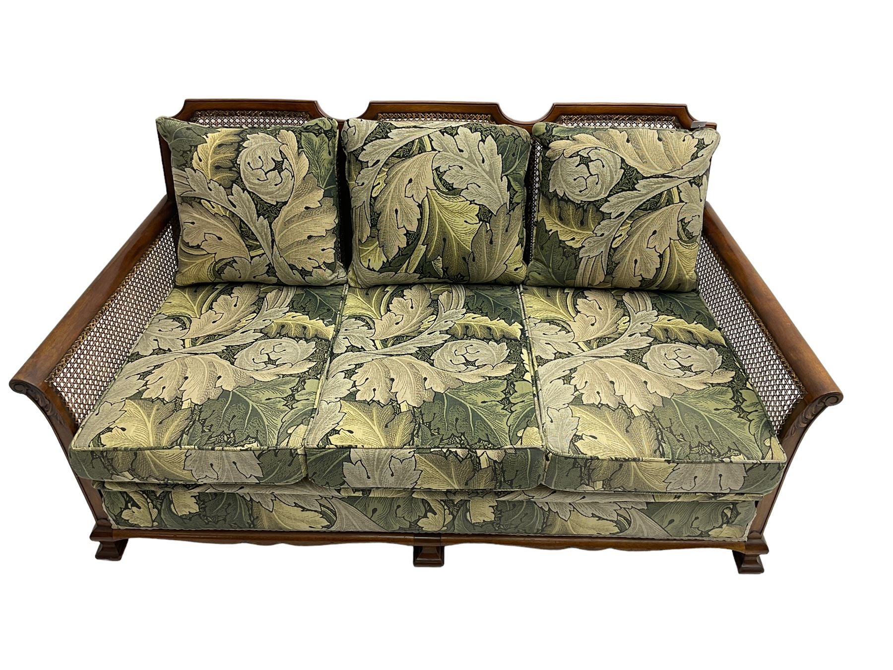 Early 20th century bergère lounge suite, mahogany framed with cane work back and sides, acanthus scroll carved uprights - three seat sofa (W167cm, H82cm, D83cm), and pair matching armchairs (W78cm), loose cushions upholstered in acanthus leaf scroll fabric with scatter cushions