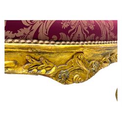 Pair of Louis XV-design giltwood stools, each upholstered in red damask fabric with slight variations in patterns, the carved frames adorned with scrolling foliage and shell motifs, raised on cabriole supports