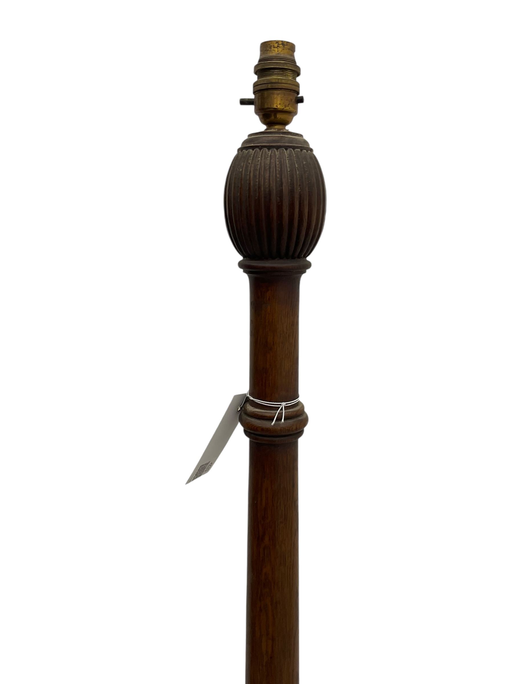 Early 20th century oak standard lamp base, of baluster form with fluted acorn finial and carved foliate decoration to the base, raised on circular plinth with bun feet