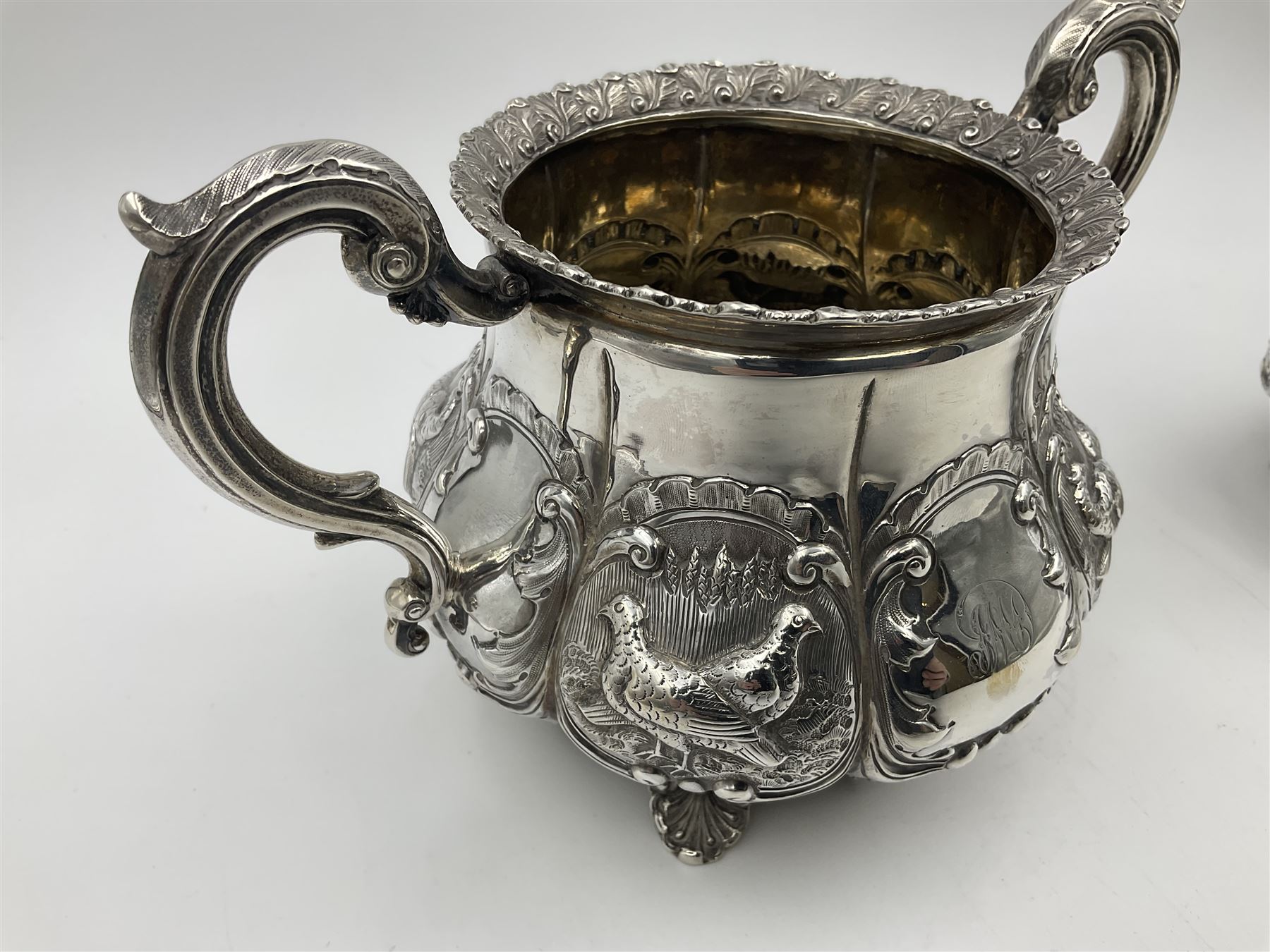 Victorian silver three piece tea service, comprising teapot, twin handled open sucrier, and milk jug, each of bellied form with acanthus capped scroll handles, the sides embossed with alternating scroll edged vacant panels and panels containing a pair of birds, upon four palmette feet, the teapot with ivory insulators to handle, and bird finial to the hinged domed cover, hallmarked William Hunter & Son, London 1861, teapot H19cm, including handles sucrier H13.5cm, including handle milk jug H12cm

This item has been registered for sale under Section 10 of the APHA Ivory Act
