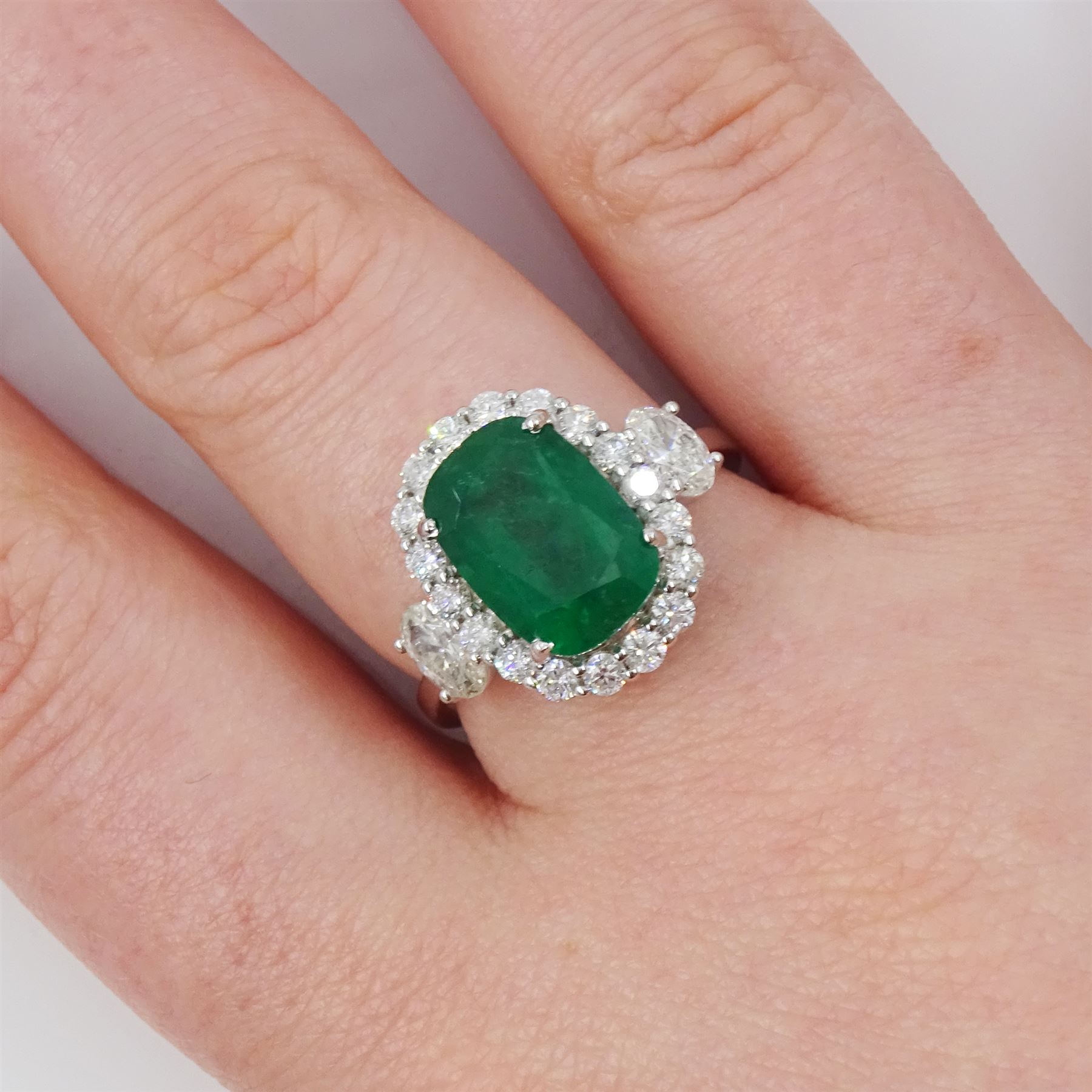 18ct white gold emerald and diamond cluster ring, single cushion cut emerald of approx 2.45 carat, surrounded by eighteen round brilliant cut diamonds, with a single oval cut diamond set either side, stamped, total diamond weight approx 1.05 carat