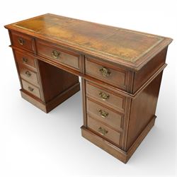 Late Victorian oak nine drawer desk, the rectangular top inset with a tooled leather writing surface bordered in gilt, above three frieze drawers and two pedestal cupboards each fitted with three graduated drawers, all with brass swan neck handles, raised on plinth bases