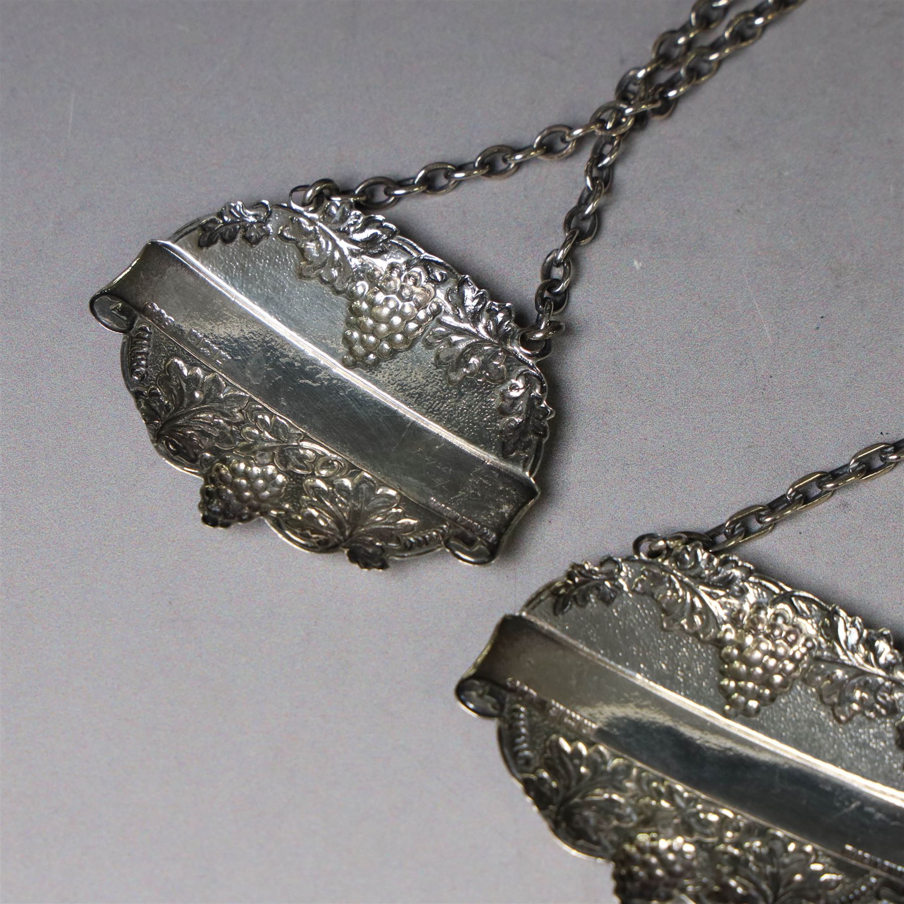 Silver bottle coaster, of circular form with turned wooden centre and pierced sides, hallmarked LGS, London 1977, together with two decanter labels, each with embossed grape vine decoration engraved Scotch and Sherry, hallmarked 