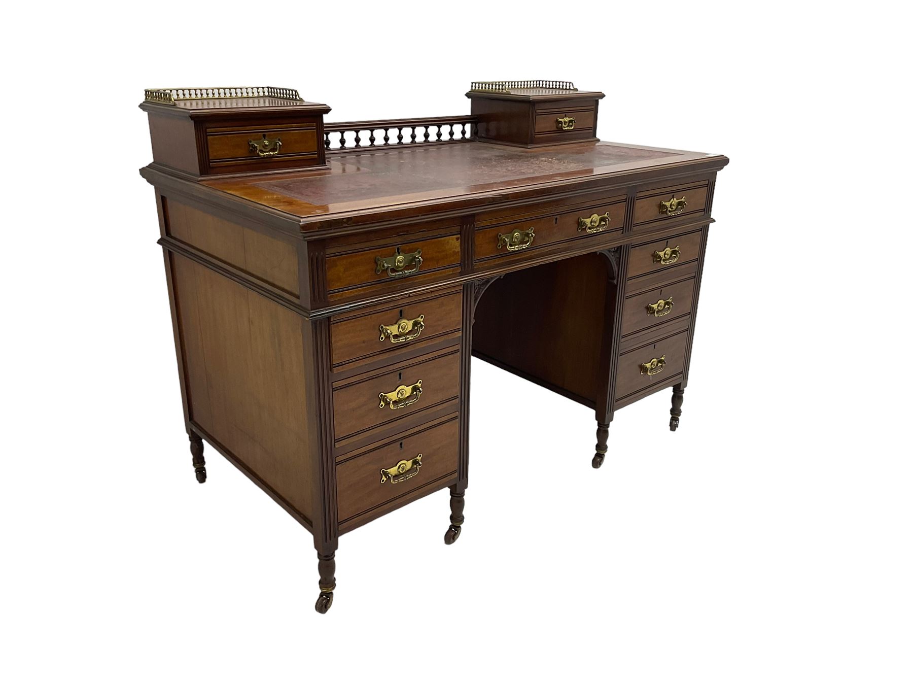 Maple & Co - Edwardian mahogany twin pedestal desk, the raised back with spindle gallery and open shelf to centre flanked by two trinket drawers, rectangular top with inset writing surface, fitted with one long and eight short graduating drawers flanked by fluted uprights, raised on brass and ceramic castors, stamped to central drawer